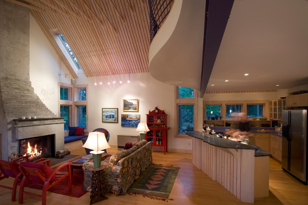 Ejemplo de sala de estar abierta contemporánea grande con paredes blancas, suelo de madera clara, todas las chimeneas, marco de chimenea de hormigón y suelo marrón