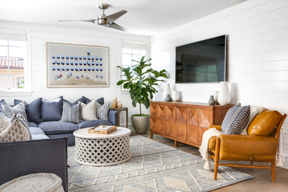 Пример оригинального дизайна: открытая гостиная комната среднего размера в морском стиле с белыми стенами, светлым паркетным полом, телевизором на стене, бежевым полом и ковром на полу без камина