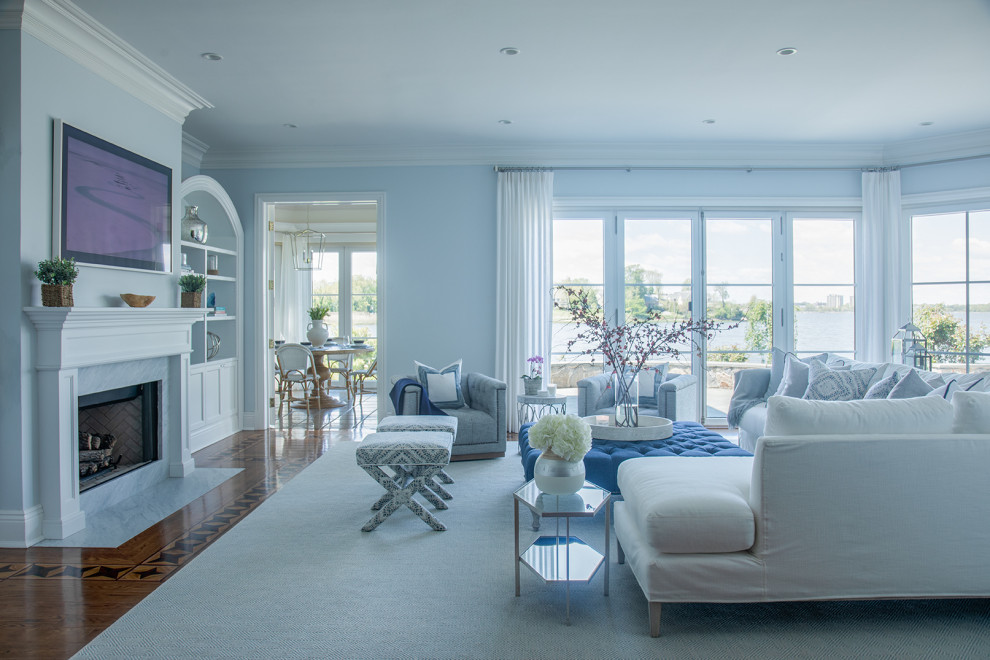 На фото: большая открытая гостиная комната в стиле неоклассика (современная классика) с синими стенами, ковровым покрытием, стандартным камином, фасадом камина из дерева и телевизором на стене