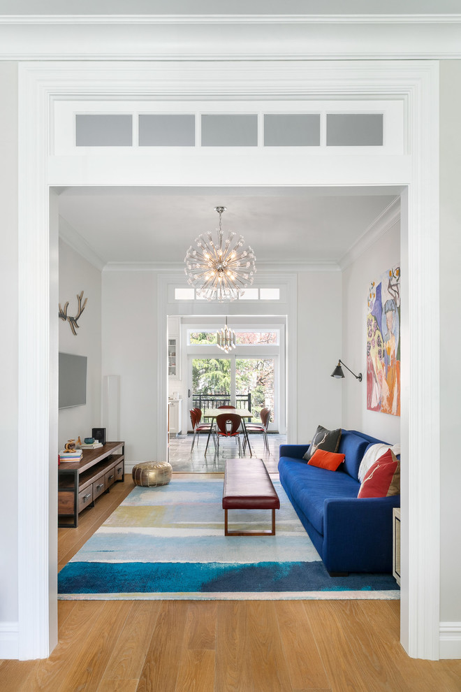 Ispirazione per un soggiorno tradizionale con pareti bianche, pavimento in legno massello medio, TV a parete e pavimento marrone