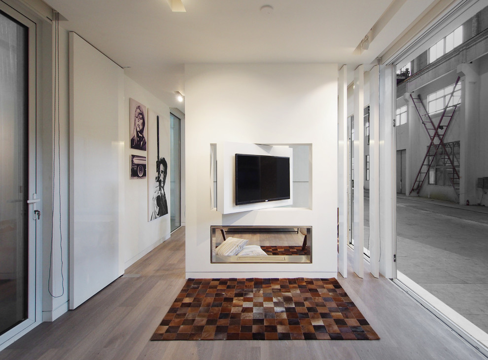 Modelo de sala de estar abierta contemporánea pequeña con paredes blancas, suelo vinílico, chimenea de doble cara, marco de chimenea de metal y televisor colgado en la pared