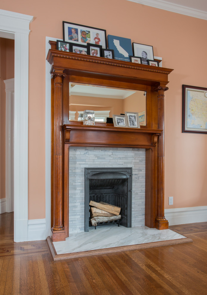 Photo of a classic enclosed games room in San Francisco with pink walls, medium hardwood flooring, a standard fireplace, a tiled fireplace surround, no tv and brown floors.