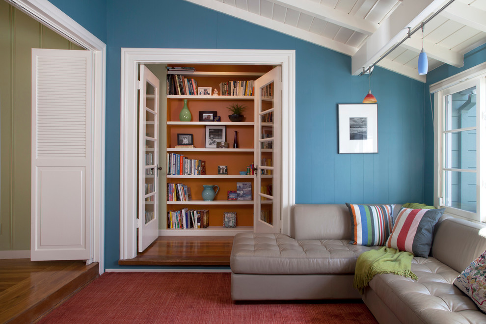 Diseño de sala de estar con biblioteca cerrada costera de tamaño medio con paredes azules y suelo de madera en tonos medios