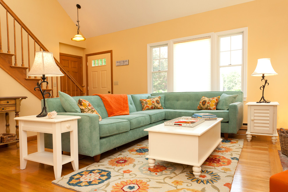 Mittelgroßes, Offenes Klassisches Wohnzimmer mit gelber Wandfarbe, braunem Holzboden, Kamin, Kaminumrandung aus Backstein und TV-Wand in Boston