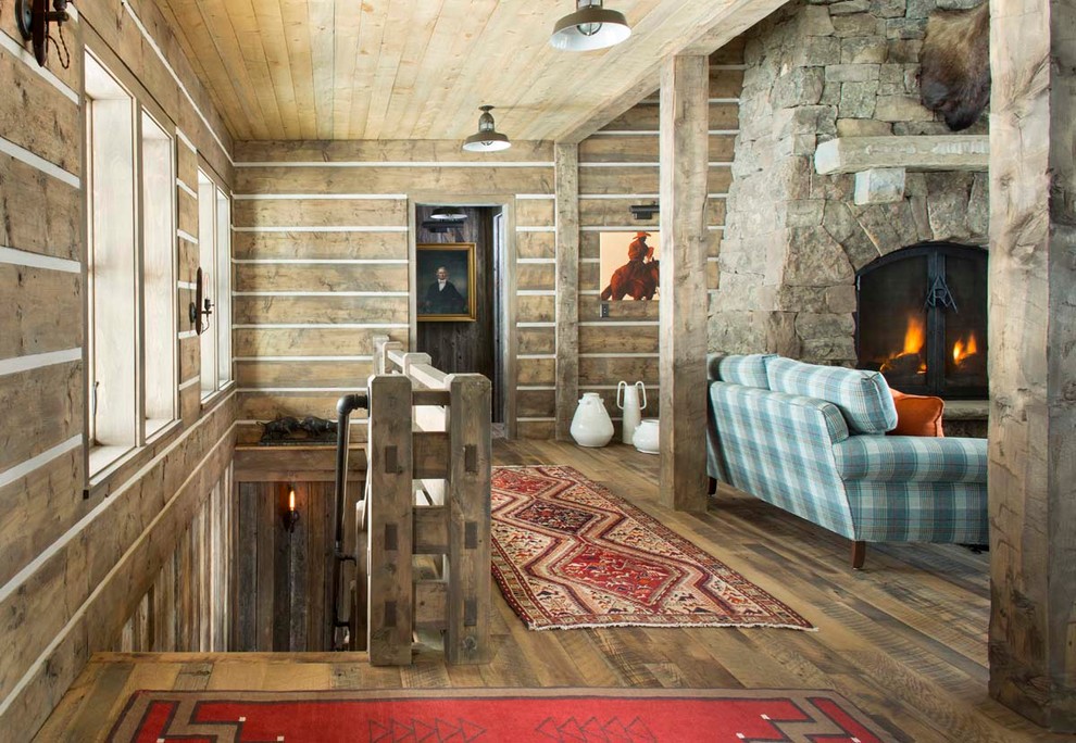 Family room library - large rustic loft-style dark wood floor family room library idea in Denver with brown walls, a standard fireplace, a stone fireplace and no tv