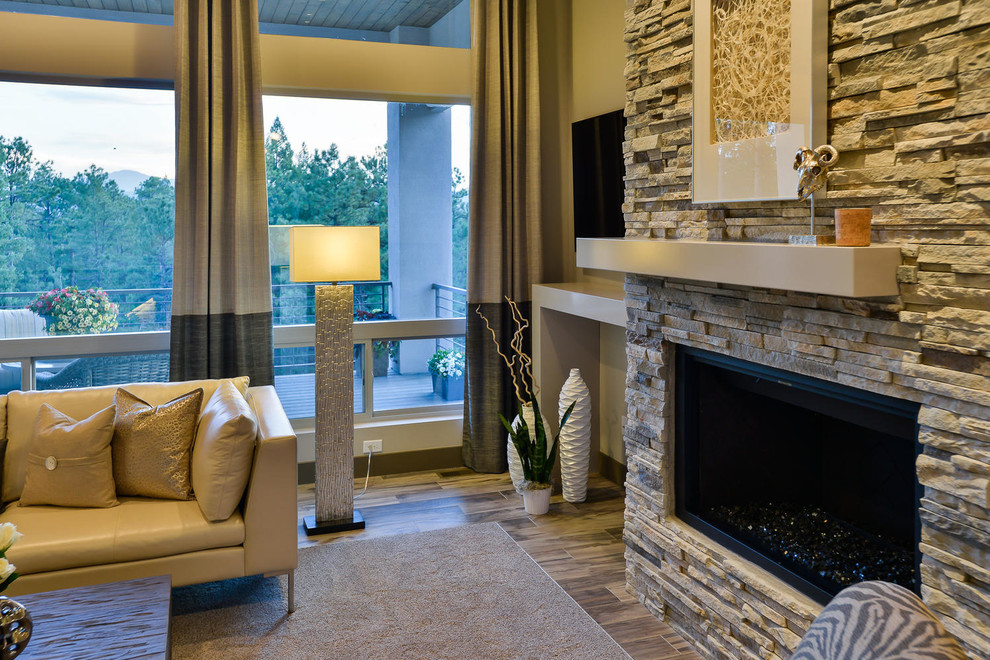 Стильный дизайн: открытая гостиная комната среднего размера в современном стиле с серыми стенами, паркетным полом среднего тона, стандартным камином, фасадом камина из камня, телевизором на стене и синим полом - последний тренд