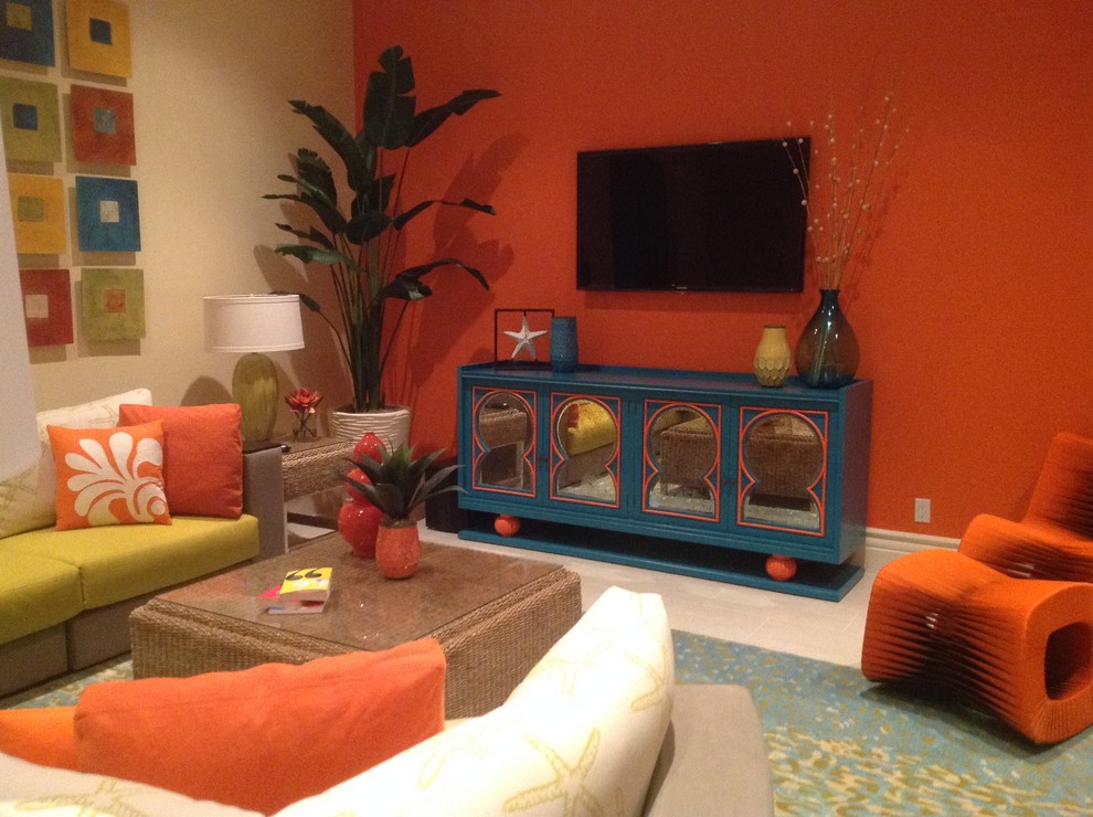 Aménagement d'une grande salle de séjour exotique ouverte avec salle de jeu, un mur orange, un sol en carrelage de porcelaine, un téléviseur fixé au mur et un sol beige.