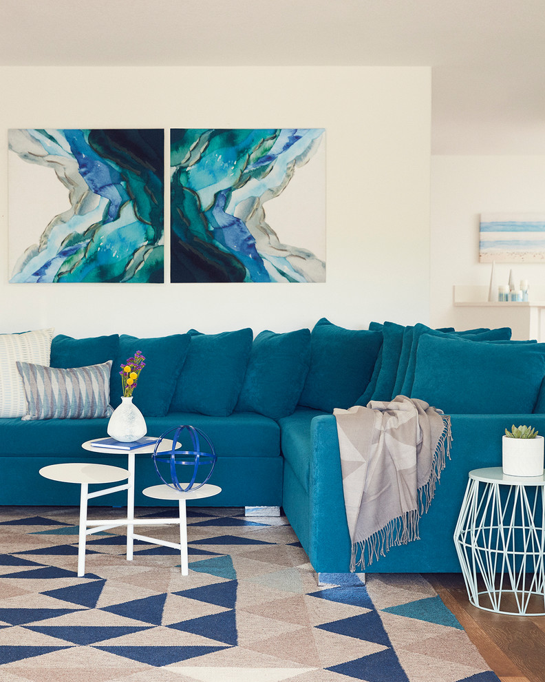 Imagen de sala de estar abierta costera con paredes blancas, suelo de madera clara y suelo marrón