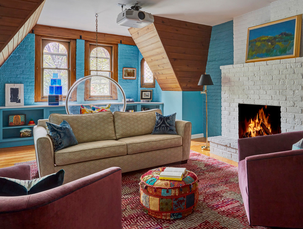 Пример оригинального дизайна: гостиная комната в стиле фьюжн с синими стенами, паркетным полом среднего тона, стандартным камином, фасадом камина из кирпича и коричневым полом
