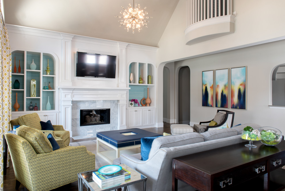 На фото: большая открытая гостиная комната в стиле неоклассика (современная классика) с серыми стенами, темным паркетным полом, стандартным камином, телевизором на стене, фасадом камина из камня и ковром на полу с