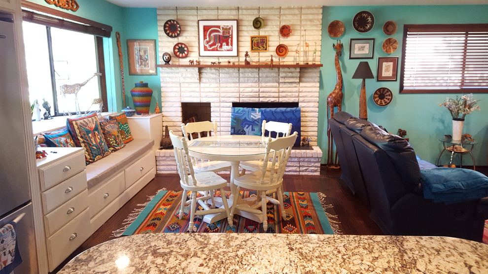 Diseño de sala de estar abierta ecléctica de tamaño medio con paredes azules, suelo de madera oscura, estufa de leña, marco de chimenea de ladrillo y televisor independiente