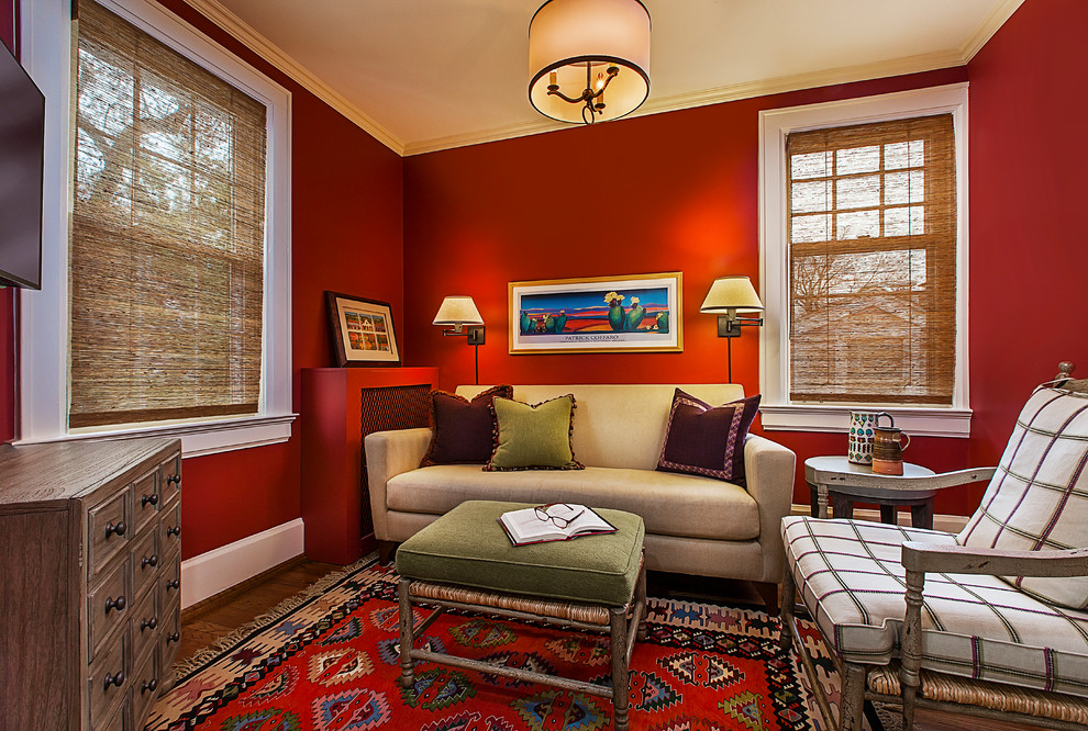Ejemplo de sala de estar con biblioteca cerrada ecléctica pequeña con paredes rojas, suelo de madera oscura, televisor colgado en la pared y suelo marrón