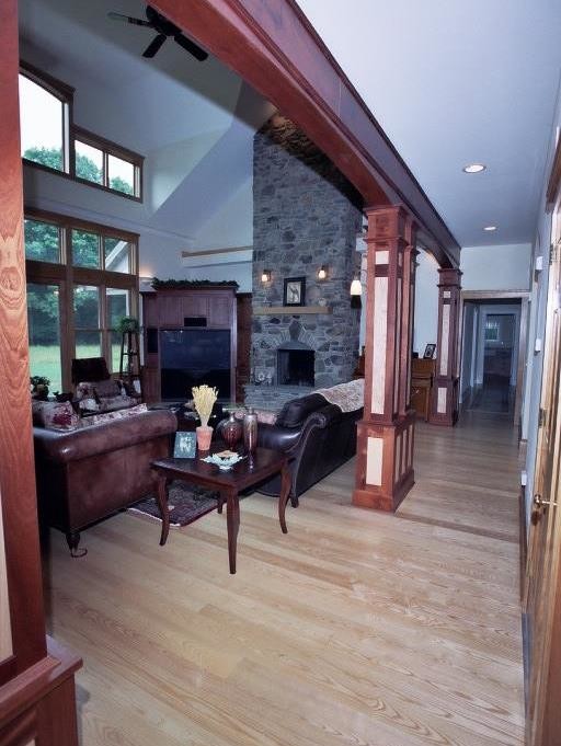 This is an example of a large classic open plan games room in Other with beige walls, light hardwood flooring, a standard fireplace, a stone fireplace surround and a built-in media unit.
