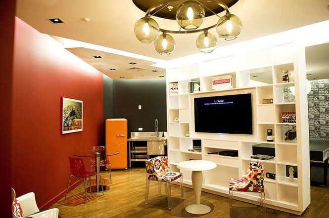На фото: большая открытая гостиная комната в современном стиле с домашним баром, красными стенами, темным паркетным полом и мультимедийным центром без камина