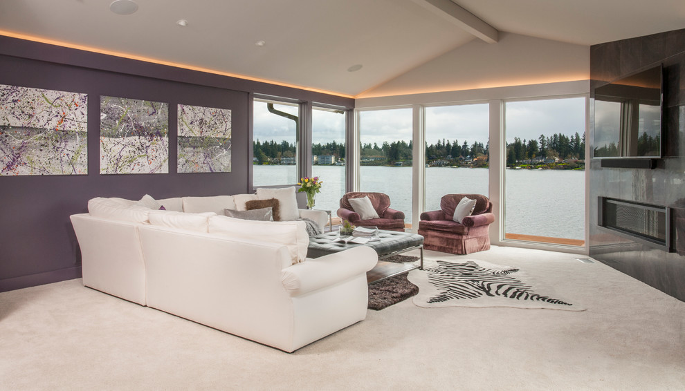 Modelo de sala de estar abierta actual de tamaño medio con paredes púrpuras, moqueta, chimenea lineal, marco de chimenea de metal y televisor colgado en la pared