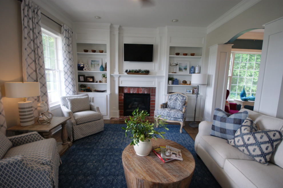 Cette image montre une salle de séjour traditionnelle de taille moyenne avec un mur gris, un sol en bois brun, une cheminée standard, un manteau de cheminée en brique et un téléviseur fixé au mur.
