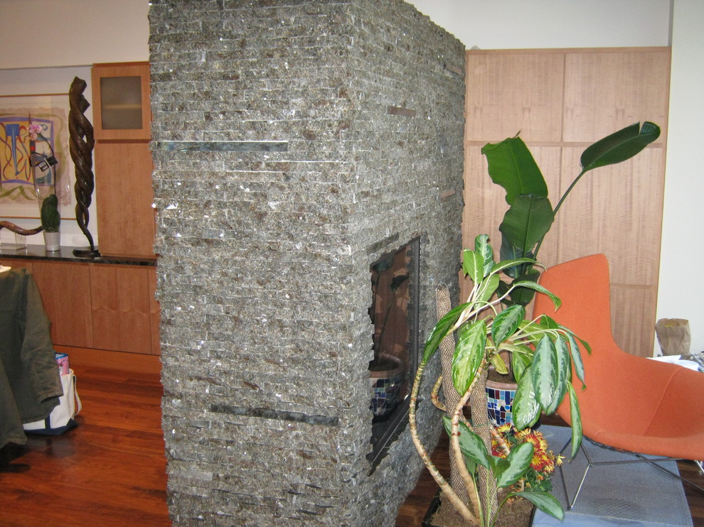 Inspiration pour une salle de séjour ethnique avec parquet foncé, une cheminée double-face et un manteau de cheminée en pierre.
