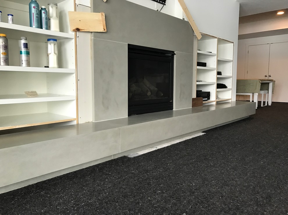Пример оригинального дизайна: гостиная комната в стиле модернизм с фасадом камина из бетона и ковром на полу