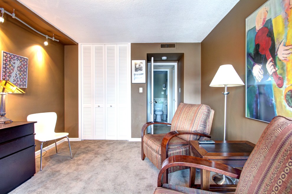 This is an example of a medium sized classic enclosed games room in Kansas City with a reading nook, brown walls, carpet and a wall mounted tv.