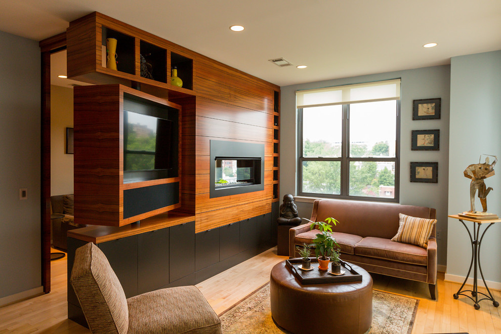 Стильный дизайн: гостиная комната в современном стиле с паркетным полом среднего тона, двусторонним камином и мультимедийным центром - последний тренд