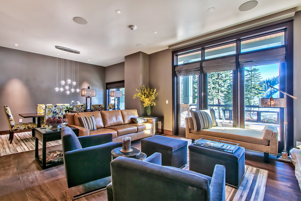 Large contemporary open plan games room in Sacramento with grey walls, dark hardwood flooring, a standard fireplace, a metal fireplace surround, a wall mounted tv and brown floors.