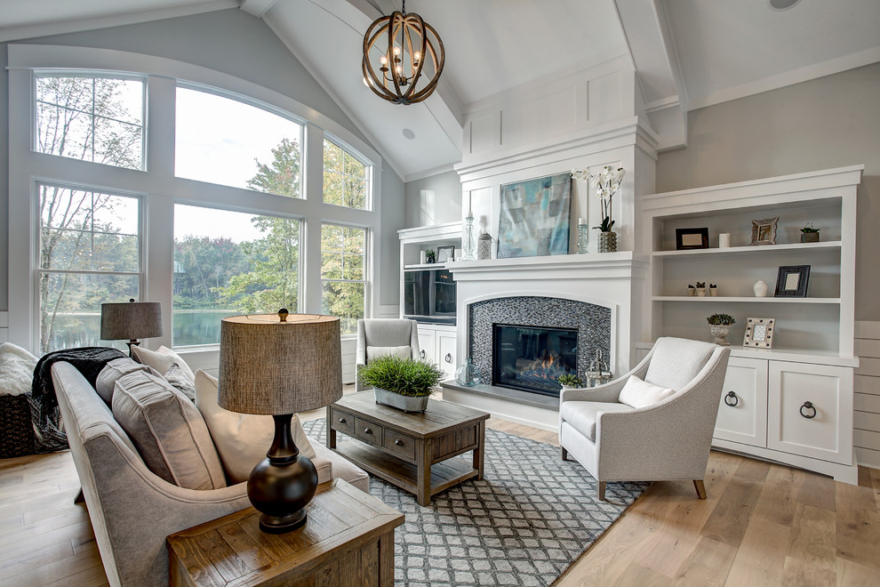 Design ideas for a classic games room in Grand Rapids with grey walls, light hardwood flooring, a standard fireplace, a tiled fireplace surround, a built-in media unit and beige floors.