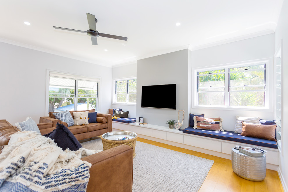 Modernes Wohnzimmer ohne Kamin mit grauer Wandfarbe, braunem Holzboden und TV-Wand in Sonstige