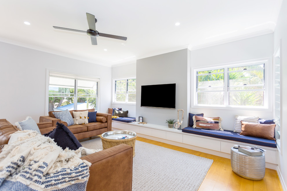 Family room - contemporary medium tone wood floor family room idea in Other with gray walls, no fireplace and a wall-mounted tv