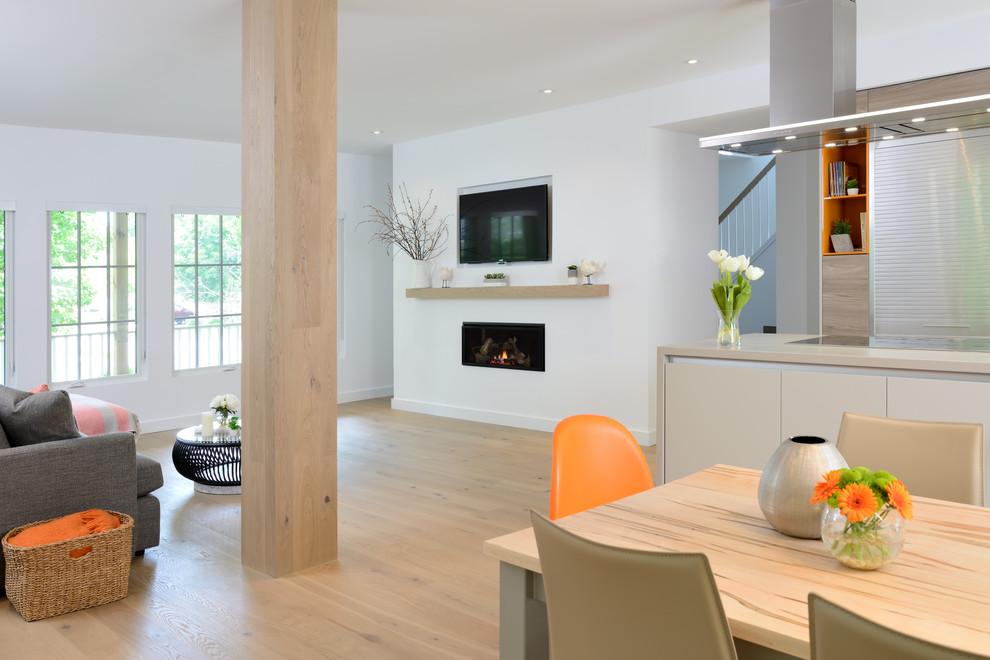 Ejemplo de sala de estar abierta contemporánea de tamaño medio con paredes blancas, suelo de madera clara, chimenea lineal, marco de chimenea de yeso y suelo beige