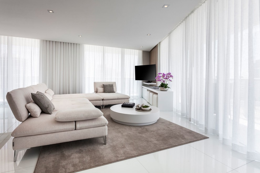 На фото: открытая гостиная комната среднего размера в современном стиле с белыми стенами, телевизором на стене, белым полом и полом из керамогранита без камина с