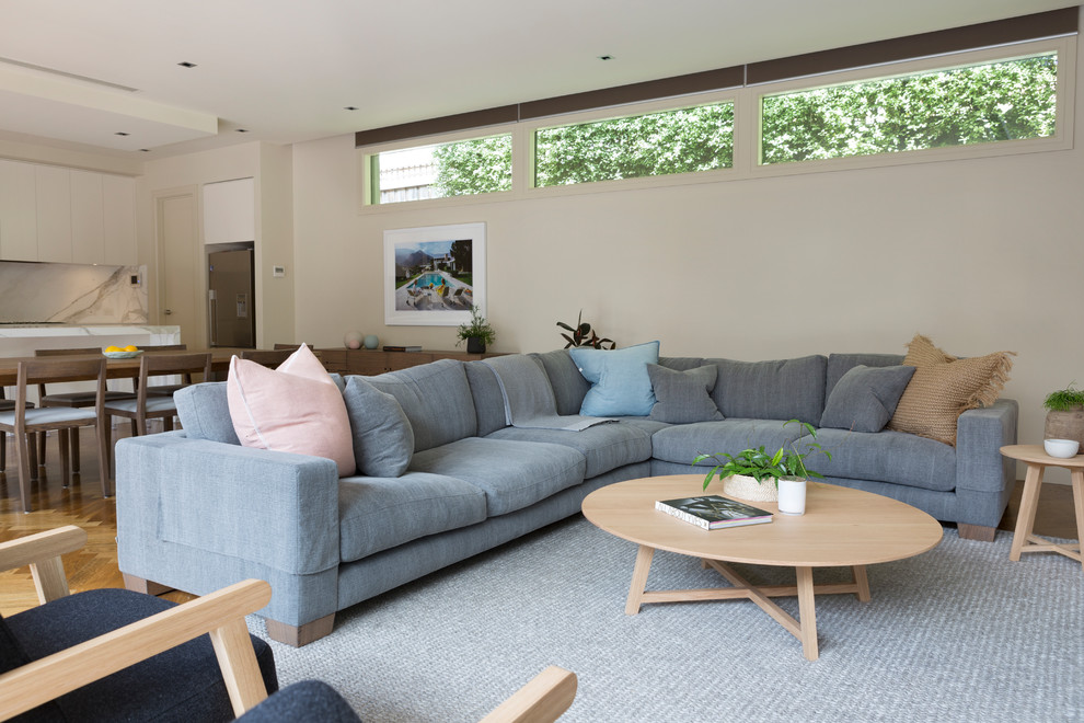 Imagen de sala de estar abierta escandinava con paredes beige, suelo de madera en tonos medios y suelo beige