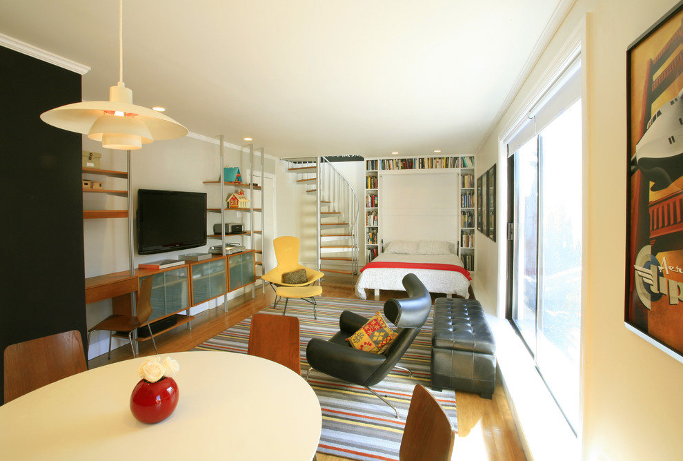 Aménagement d'une salle de séjour contemporaine ouverte avec un mur beige, un sol en bois brun, aucune cheminée et un téléviseur fixé au mur.