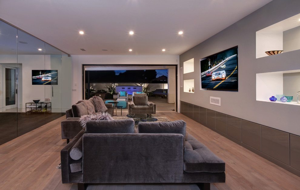 Esempio di un soggiorno minimal con pareti grigie, pavimento in legno massello medio e TV a parete