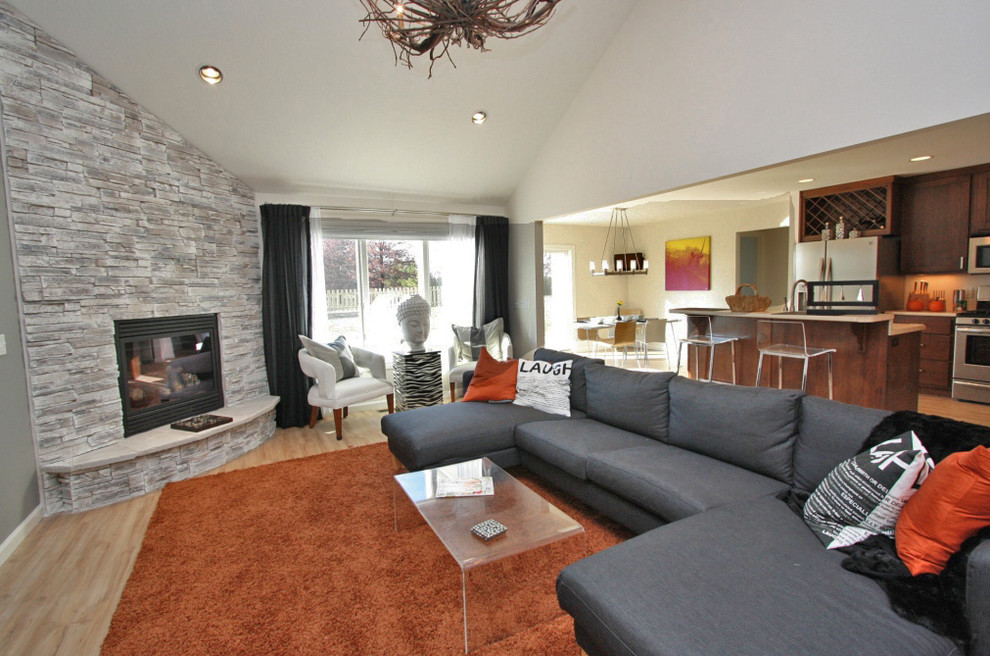 Imagen de sala de estar contemporánea con chimenea de esquina y marco de chimenea de piedra