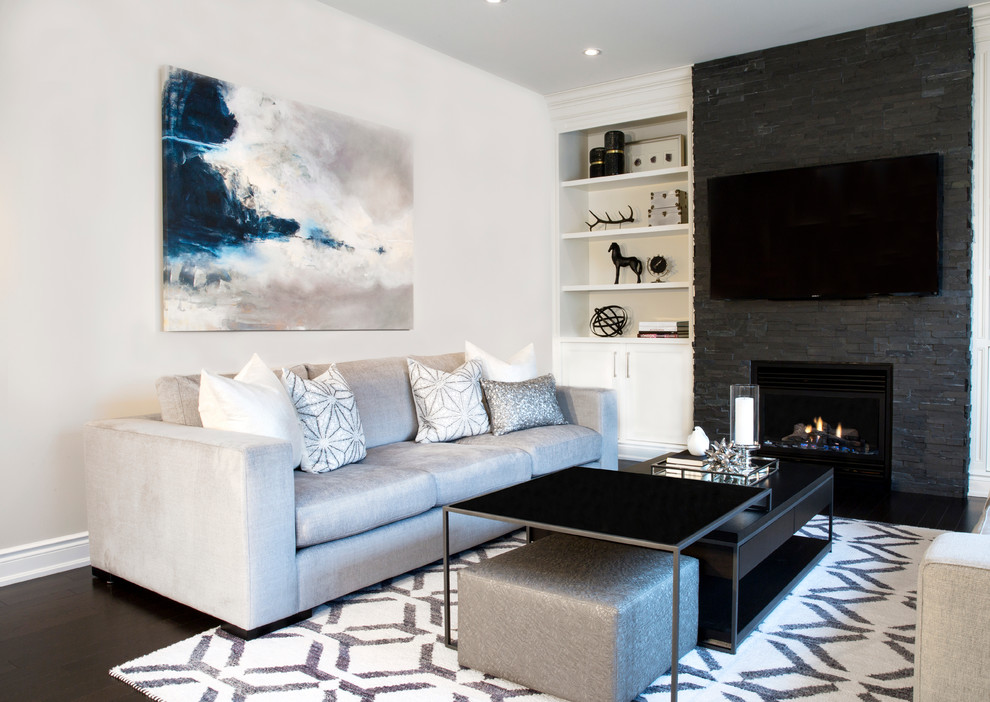 Diseño de sala de estar contemporánea con paredes grises, suelo de madera oscura, marco de chimenea de piedra y pared multimedia