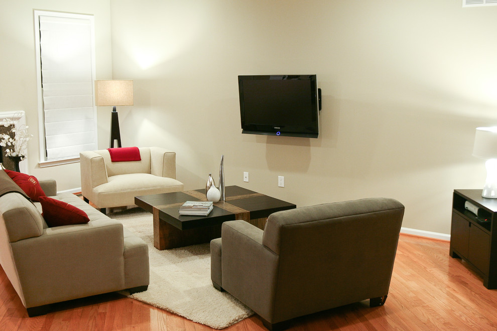 Ispirazione per un piccolo soggiorno design chiuso con pareti beige, parquet chiaro e TV a parete