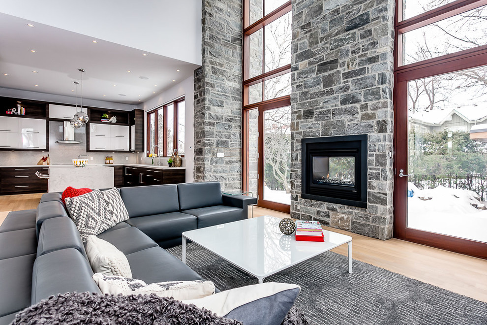 Cette image montre une salle de séjour design ouverte avec une cheminée double-face, un manteau de cheminée en pierre et aucun téléviseur.