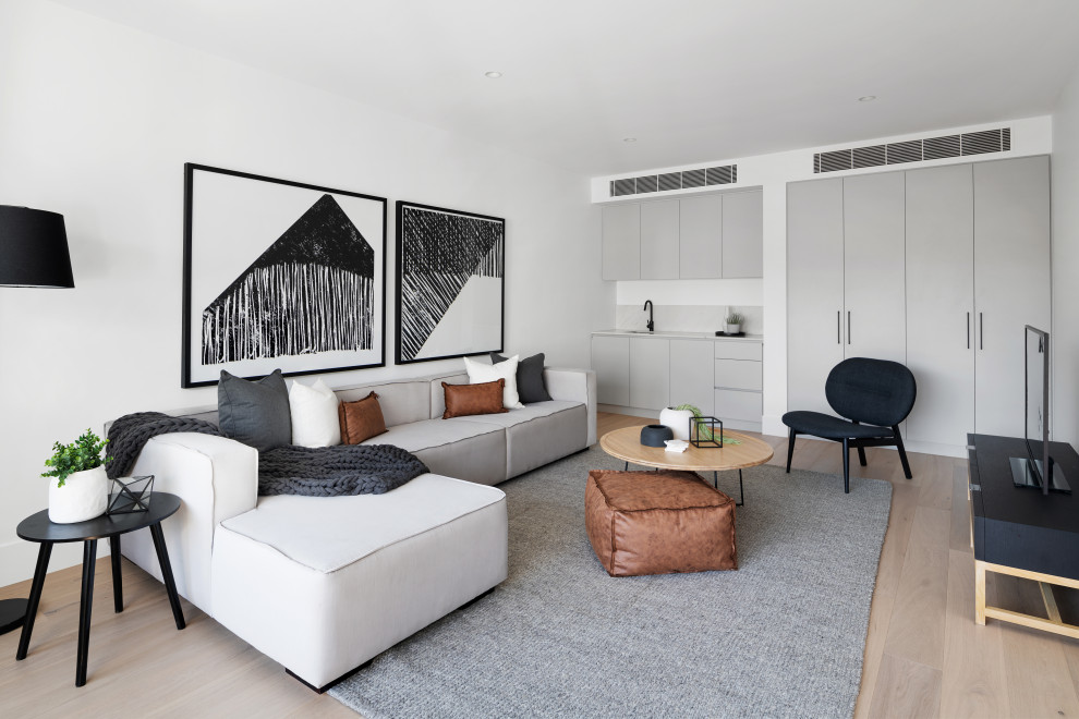 Пример оригинального дизайна: гостиная комната в современном стиле с белыми стенами, светлым паркетным полом и бежевым полом