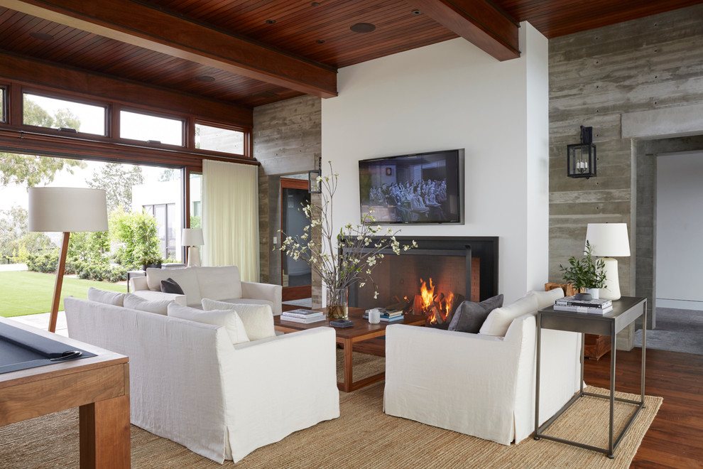 Offenes Modernes Wohnzimmer mit Kamin, TV-Wand und braunem Holzboden in Los Angeles