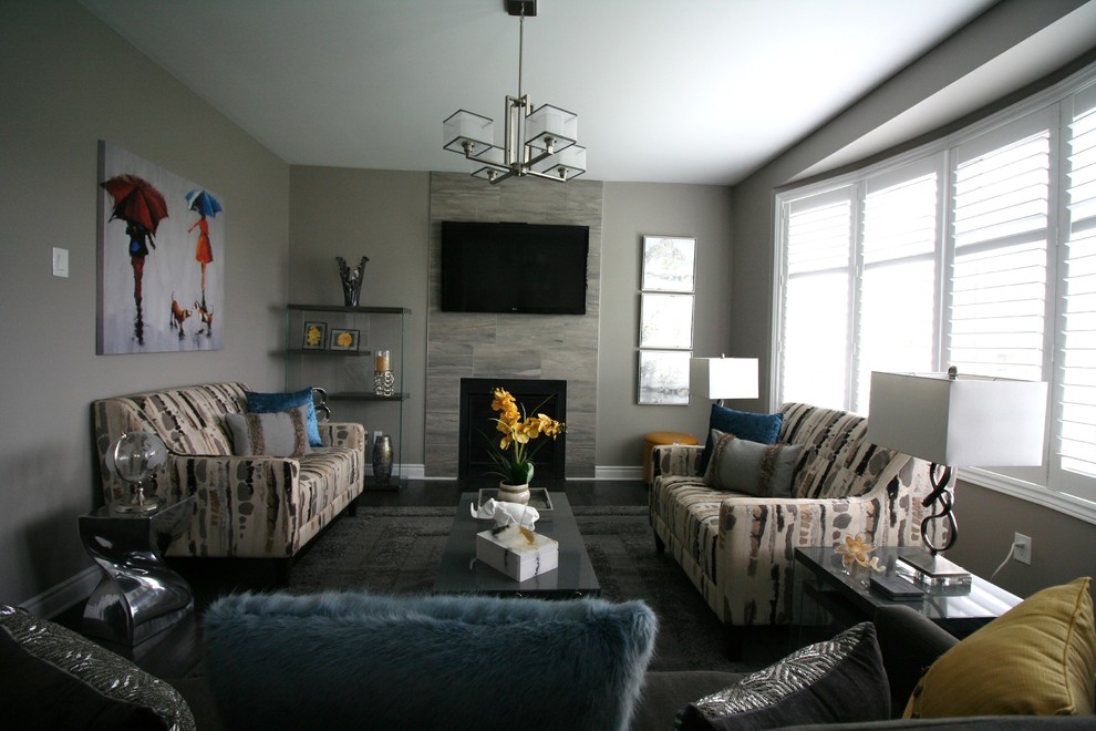 На фото: открытая гостиная комната среднего размера в современном стиле с серыми стенами, темным паркетным полом, стандартным камином, фасадом камина из плитки, телевизором на стене и серым полом