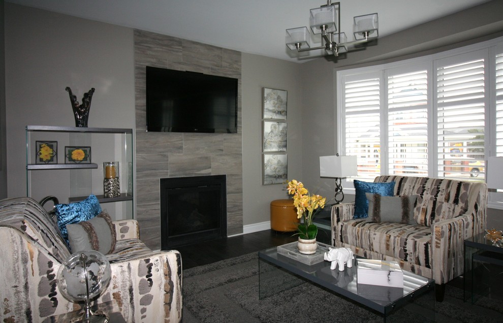 Mid-sized trendy open concept dark wood floor and gray floor family room photo in Ottawa with gray walls, a standard fireplace, a tile fireplace and a wall-mounted tv