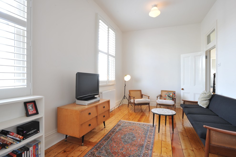 Esempio di un soggiorno minimal chiuso e di medie dimensioni con pareti bianche, pavimento in legno massello medio, TV autoportante e pavimento arancione