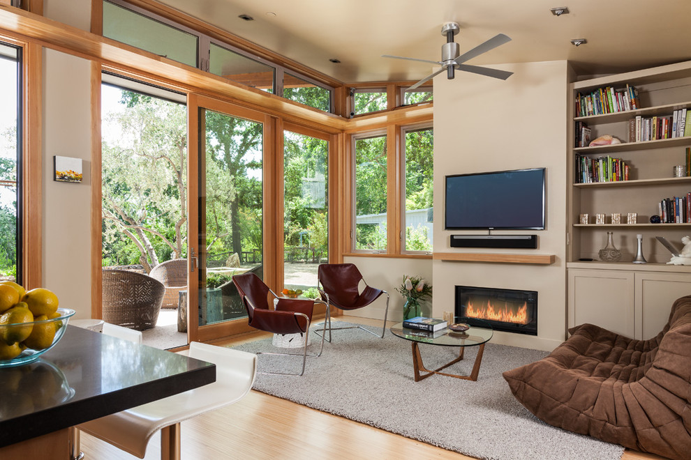 This is an example of a contemporary open plan games room in San Francisco with a reading nook, beige walls, light hardwood flooring, a ribbon fireplace and a wall mounted tv.