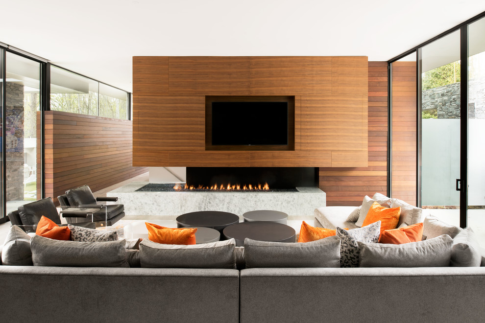 Modelo de sala de estar abierta actual grande con chimenea de doble cara, paredes marrones y pared multimedia