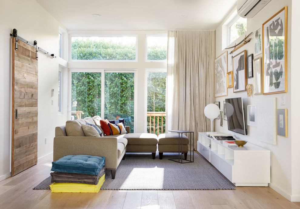 Источник вдохновения для домашнего уюта: большая открытая гостиная комната в современном стиле с белыми стенами, светлым паркетным полом, телевизором на стене и бежевым полом без камина
