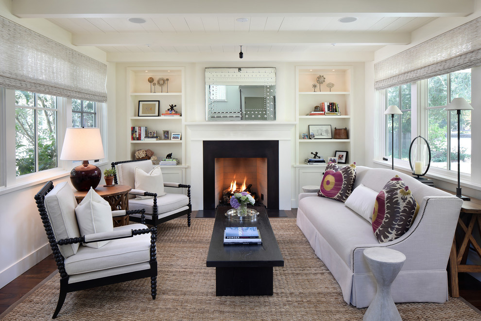 На фото: гостиная комната в стиле кантри с белыми стенами, темным паркетным полом, стандартным камином и коричневым полом с
