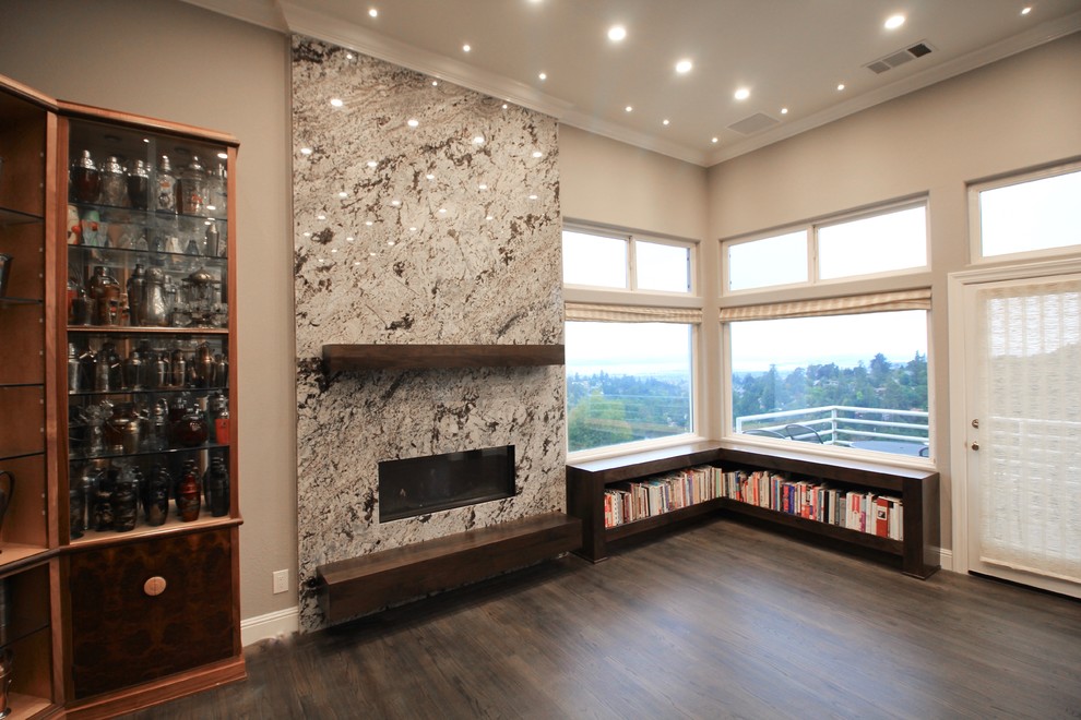 Imagen de sala de estar abierta contemporánea de tamaño medio con paredes grises, suelo de madera oscura, chimenea lineal, marco de chimenea de piedra y suelo marrón