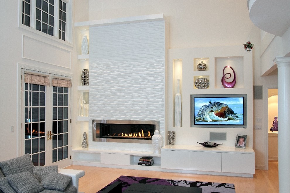 Imagen de sala de estar abierta actual extra grande con paredes blancas, suelo de madera en tonos medios, todas las chimeneas, marco de chimenea de yeso y pared multimedia