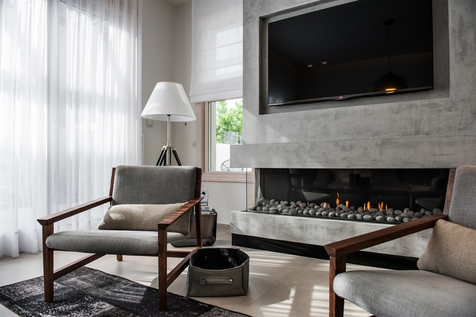 Imagen de sala de estar actual de tamaño medio con paredes grises, suelo de madera en tonos medios, marco de chimenea de hormigón y pared multimedia