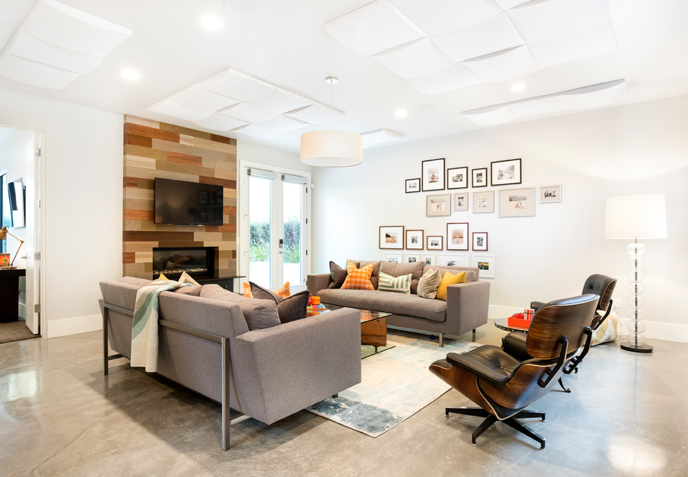 На фото: гостиная комната в современном стиле с белыми стенами, бетонным полом, двусторонним камином, фасадом камина из дерева и серым полом с